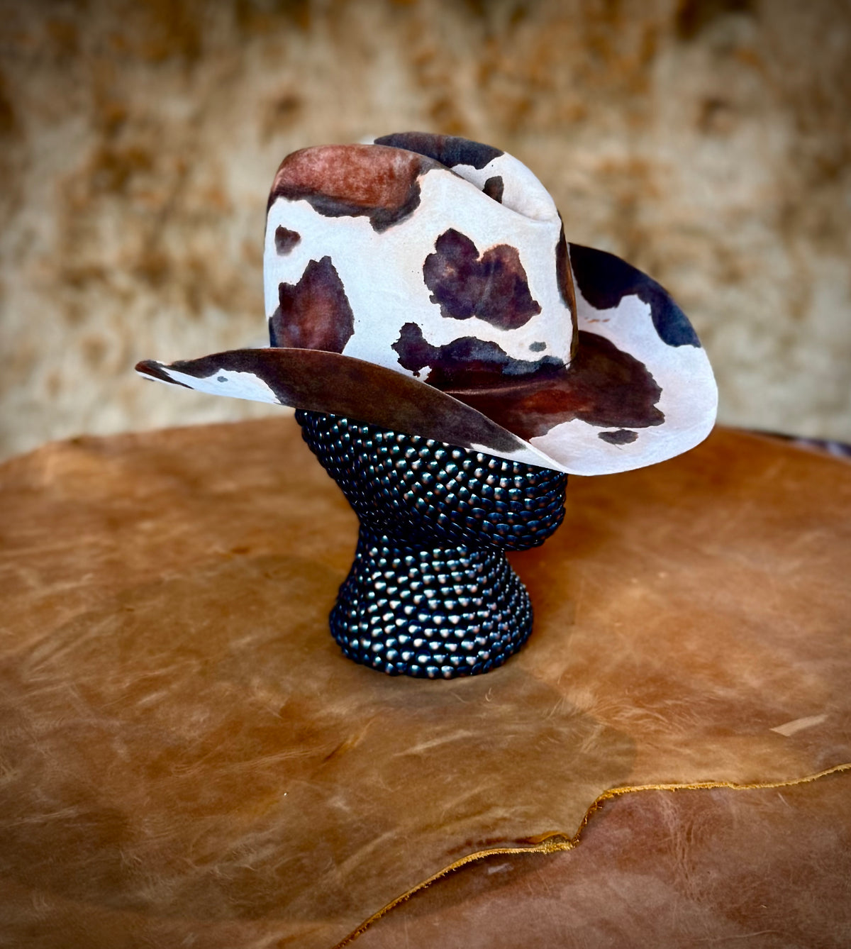 CowHide Crown limited-edition cowhide hat displayed on a black textured mannequin over a leather surface