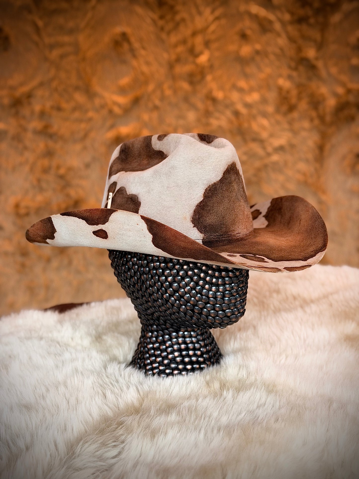 CowHide Crown cow print cowboy hat in profile on a stand — TROVADOR