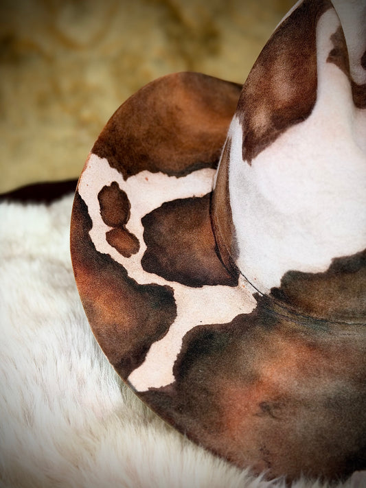 Close-up of the CowHide Crown cow print cowboy hat — hand-dyed brown cowhide markings on bone beaver felt